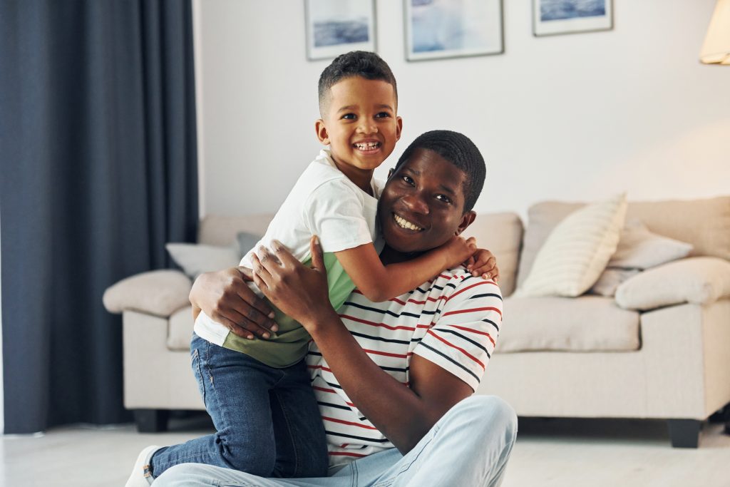 father and son sitting on living room floor waiting for furnace repair tech